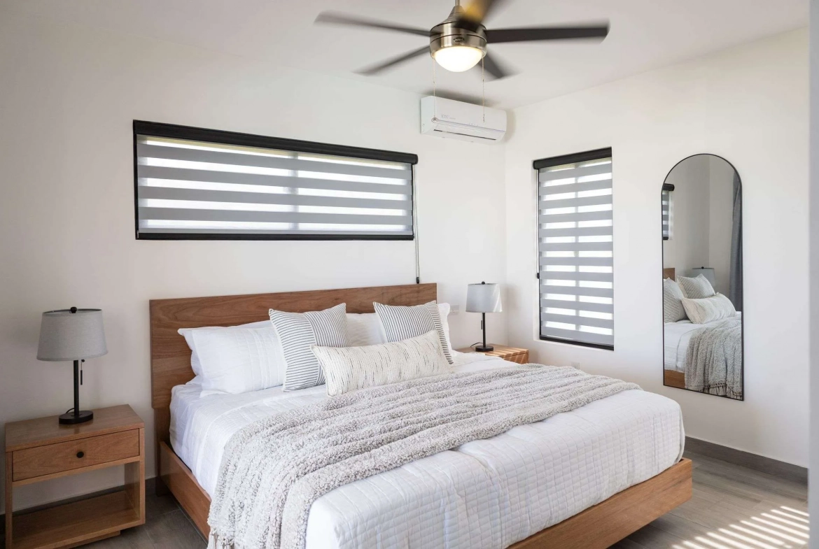 buyDRproperty Modern bedroom with king-size bed, white bedding, and striped pillows Sosua Real Estate