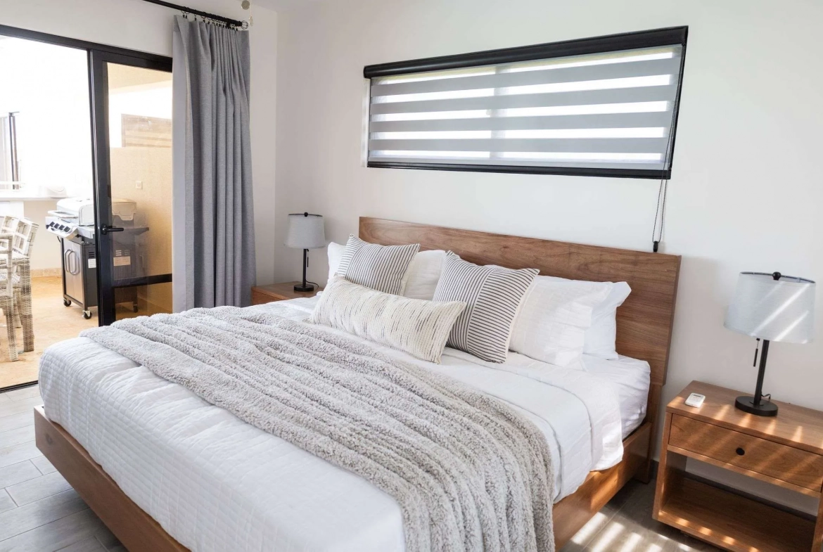 buyDRproperty Modern bedroom with king-size bed, white linens, and wooden nightstands Sosua Real Estate
