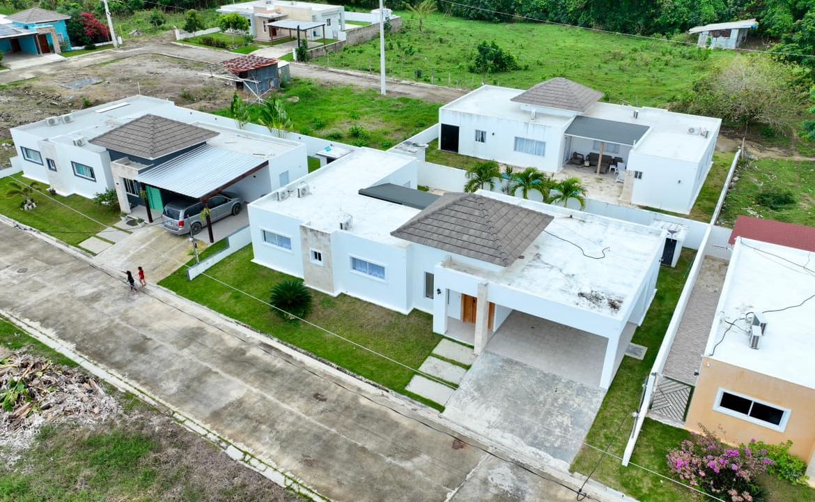 Modern white houses with brown tiled roofs in a green suburban neighborhood