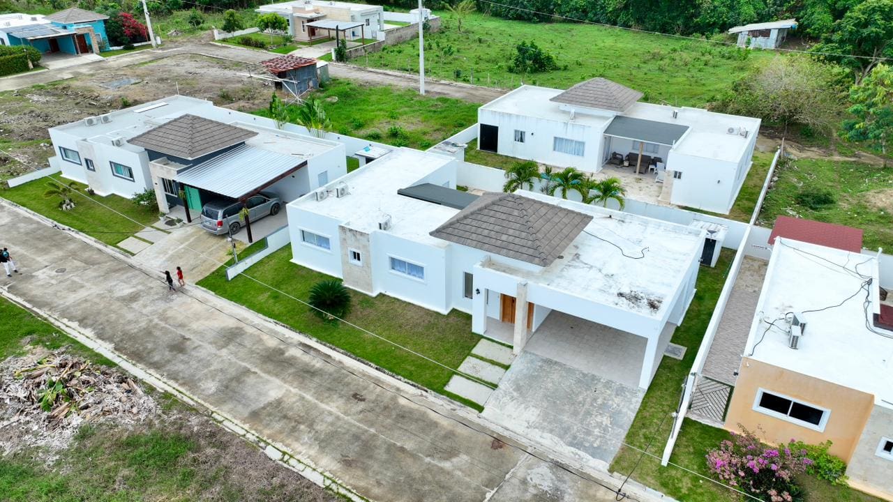 Modern white houses with brown tiled roofs in a green suburban neighborhood