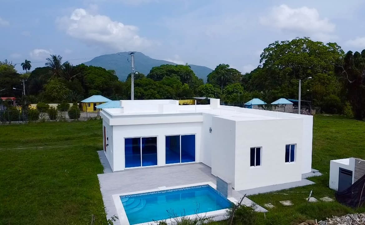 Modern white house with blue-windowed doors and a swimming pool Sosua Real Estate