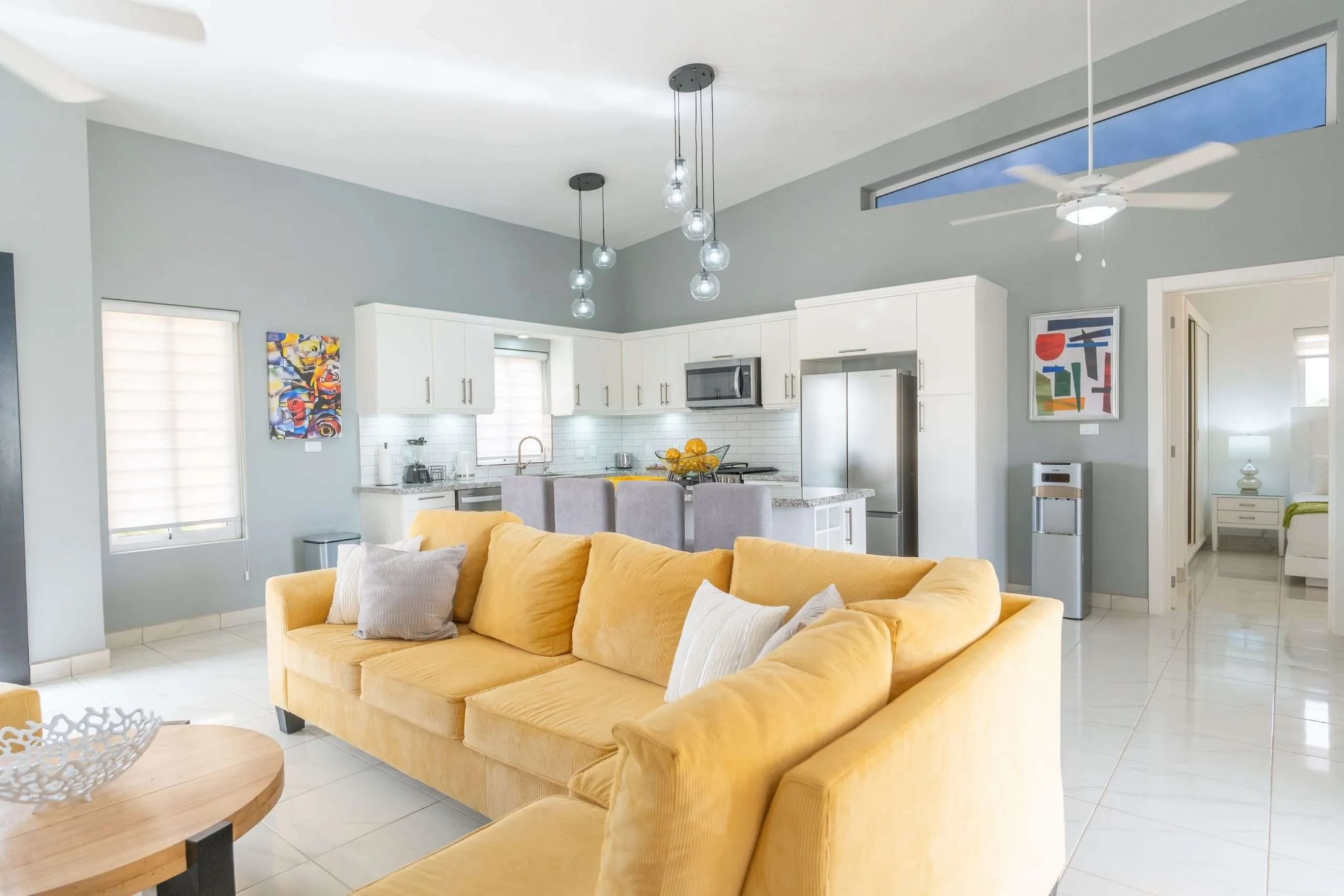 buyDRproperty Bright, modern living room with yellow sectional sofa and open-plan kitchen Sosua Real Estate