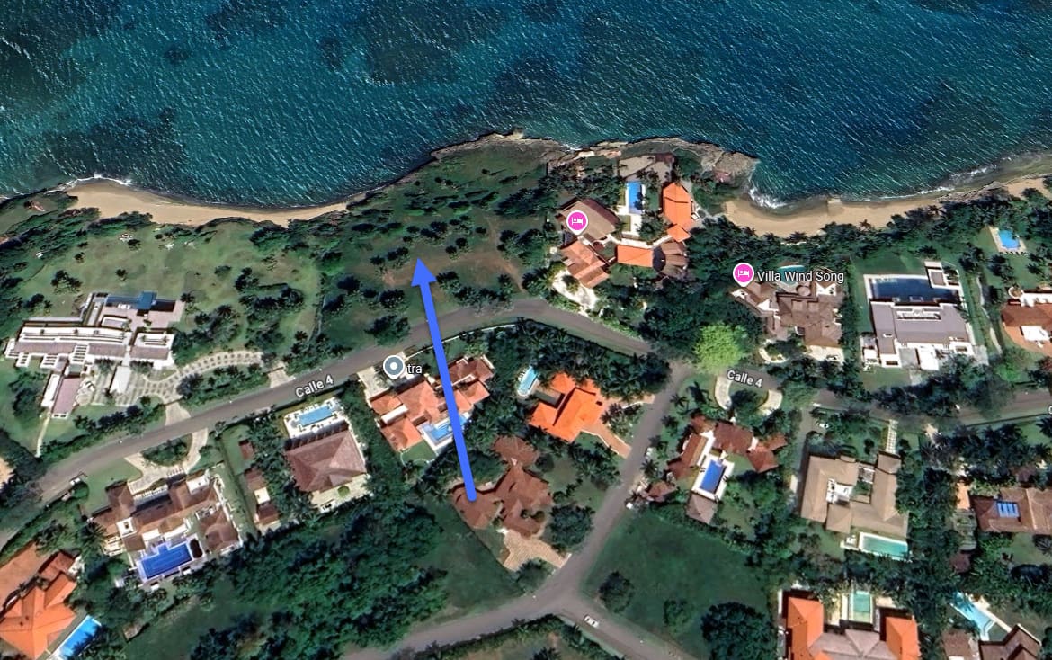 Aerial view of luxury villas and coastal landscape with blue arrow indicating direction