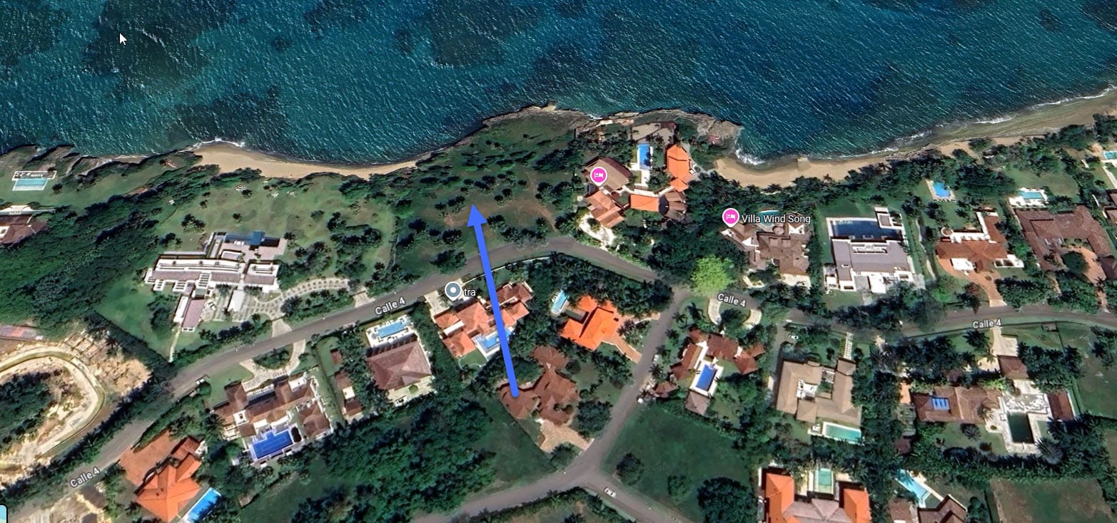 Aerial view of luxury villas and coastal landscape with blue arrow indicating direction