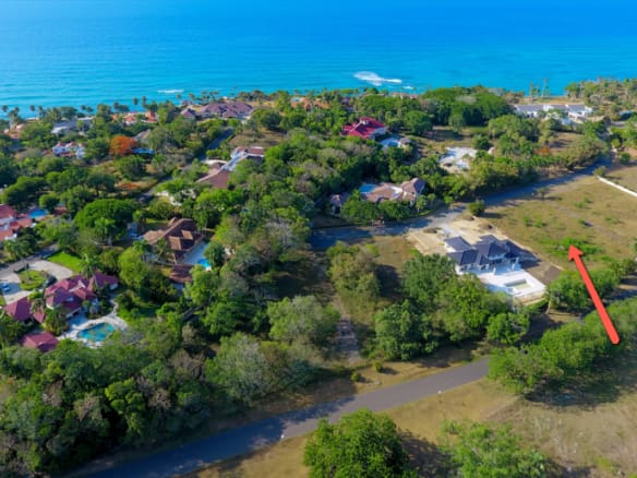 Aerial view of luxury beachfront villas and lush tropical landscaping near the ocean.