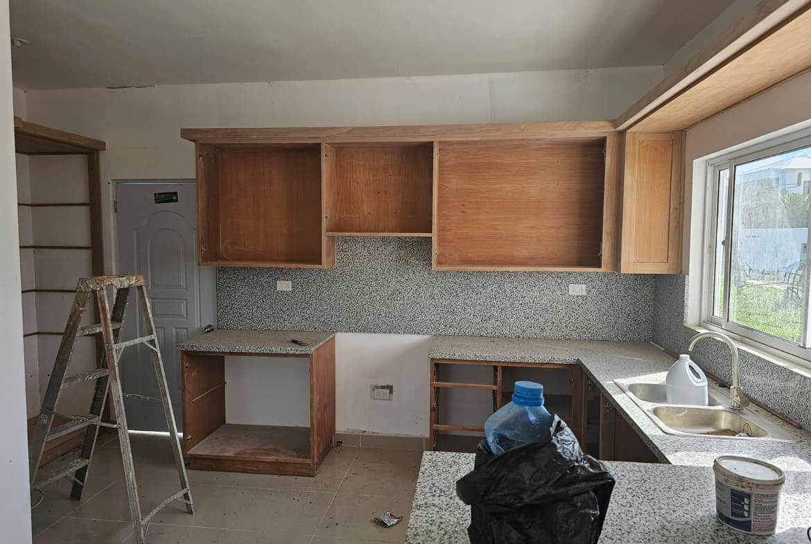 Kitchen renovation: unfinished wooden cabinets, granite countertops, and speckled backsplash.