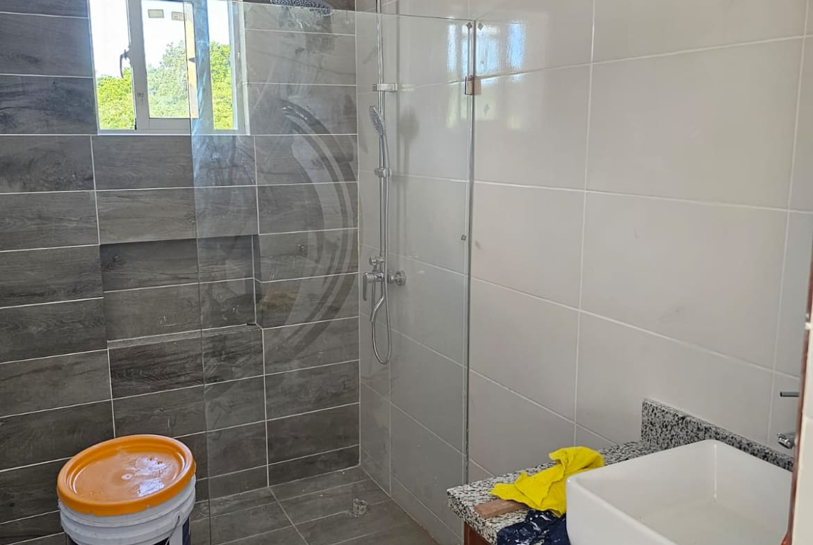 Modern bathroom renovation with tiled walls, glass shower enclosure, and sink