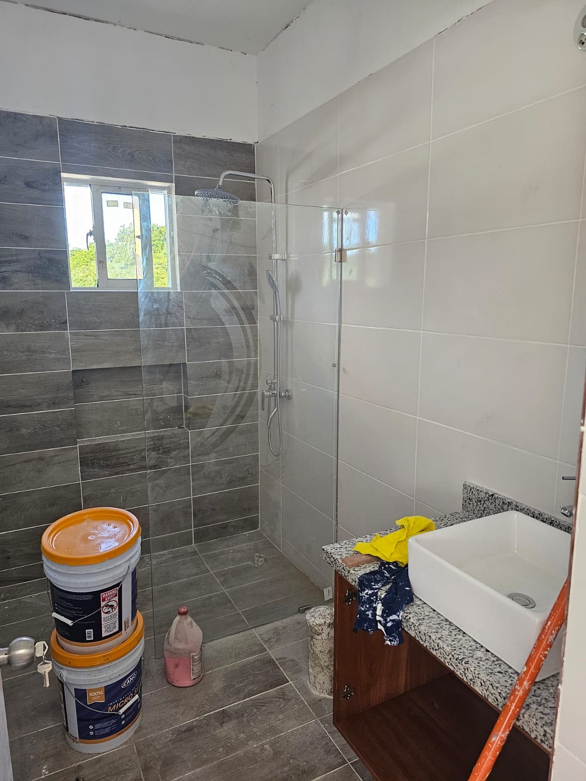 Modern bathroom renovation with tiled walls, glass shower enclosure, and sink