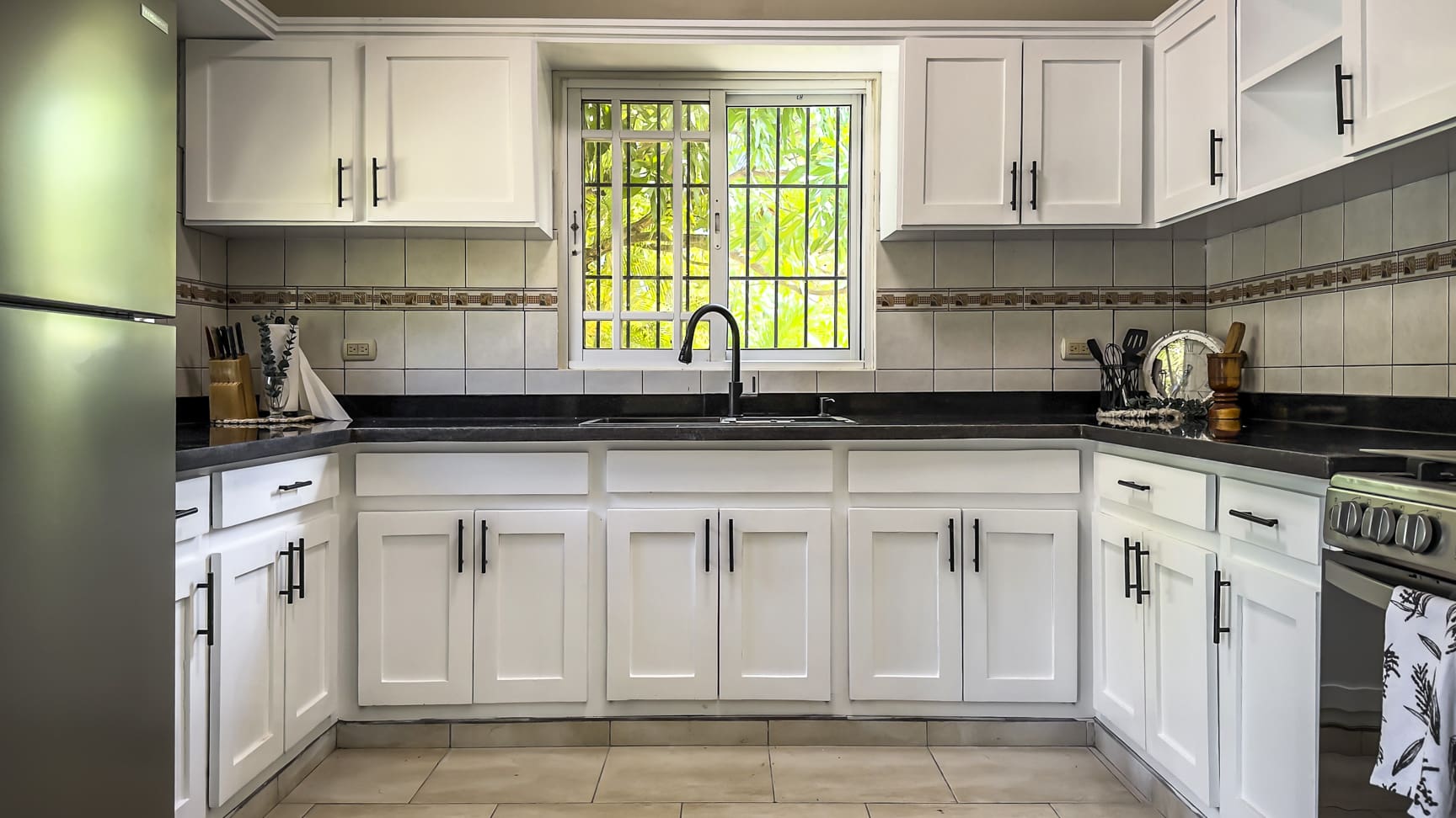 White kitchen cabinets and countertops with a sink and window view.