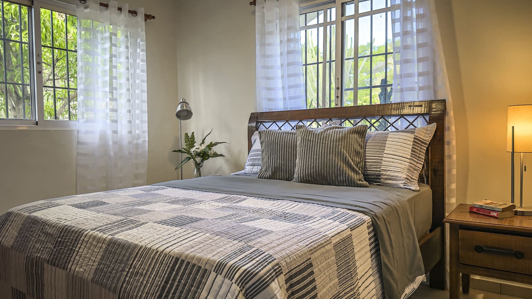 Cozy bedroom with a queen-size bed, striped bedding, and large windows with sheer curtains.