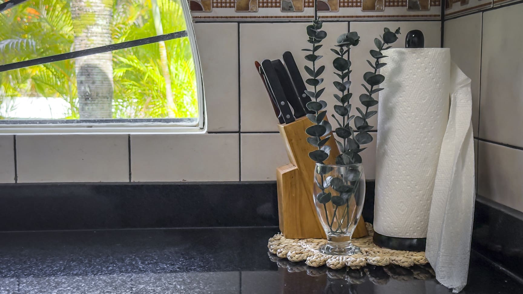 Kitchen counter with knife block, eucalyptus in a vase, and paper towel holder.