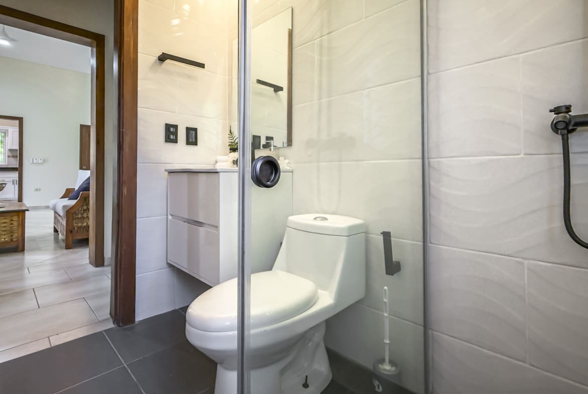 Modern bathroom with white toilet, glass shower, and sleek vanity