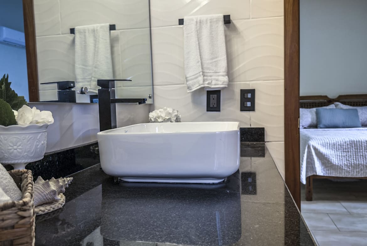 Modern bathroom with white vessel sink, black faucet, and towels