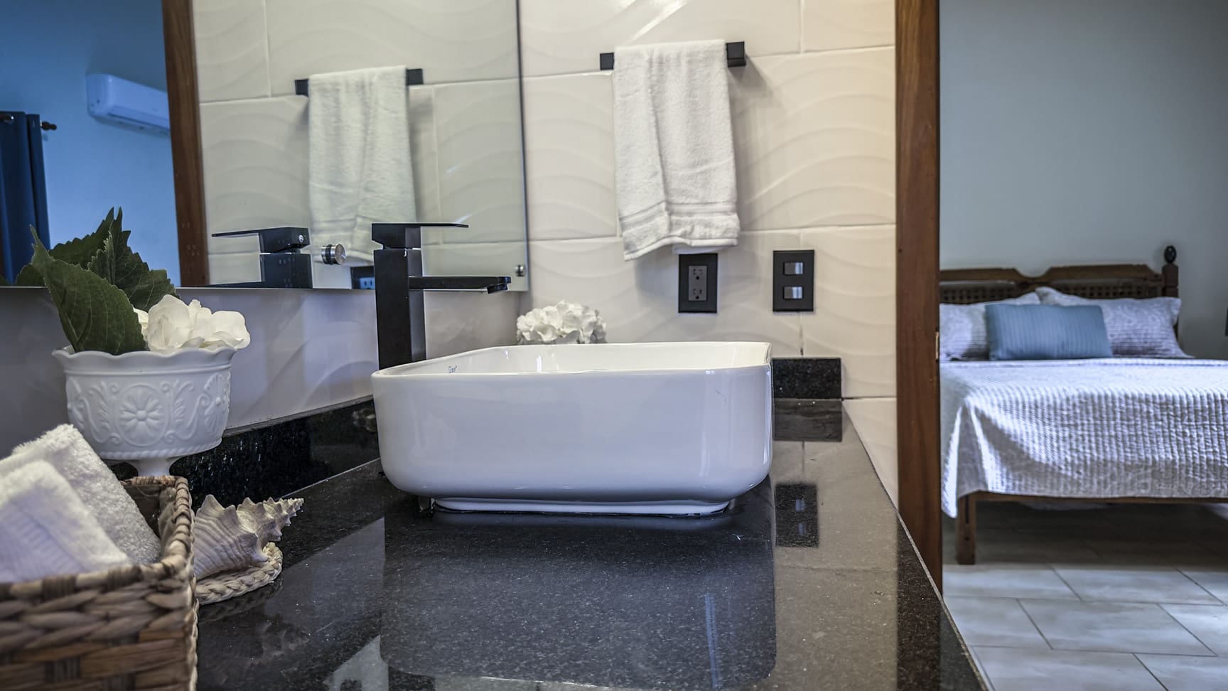 Modern bathroom with white vessel sink, black faucet, and towels
