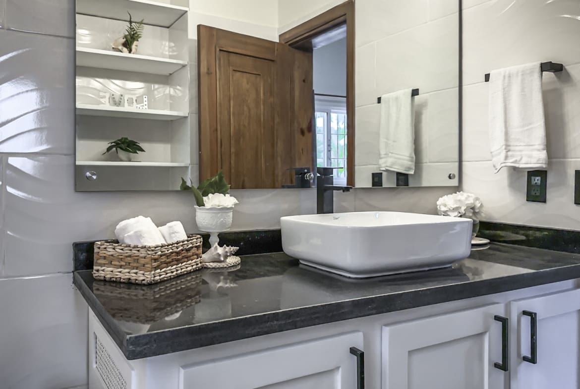 Modern bathroom vanity with white square vessel sink, black faucet, and white towels.
