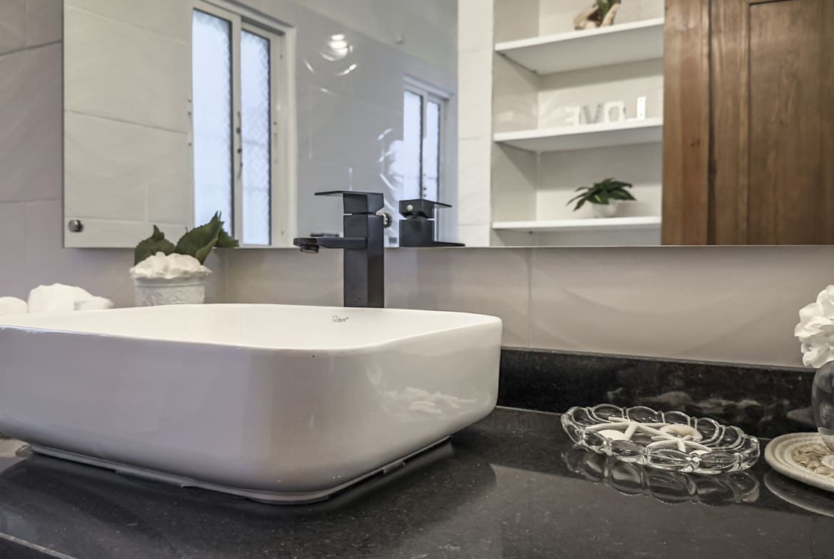 Modern bathroom with white vessel sink, black faucet, and granite countertop.
