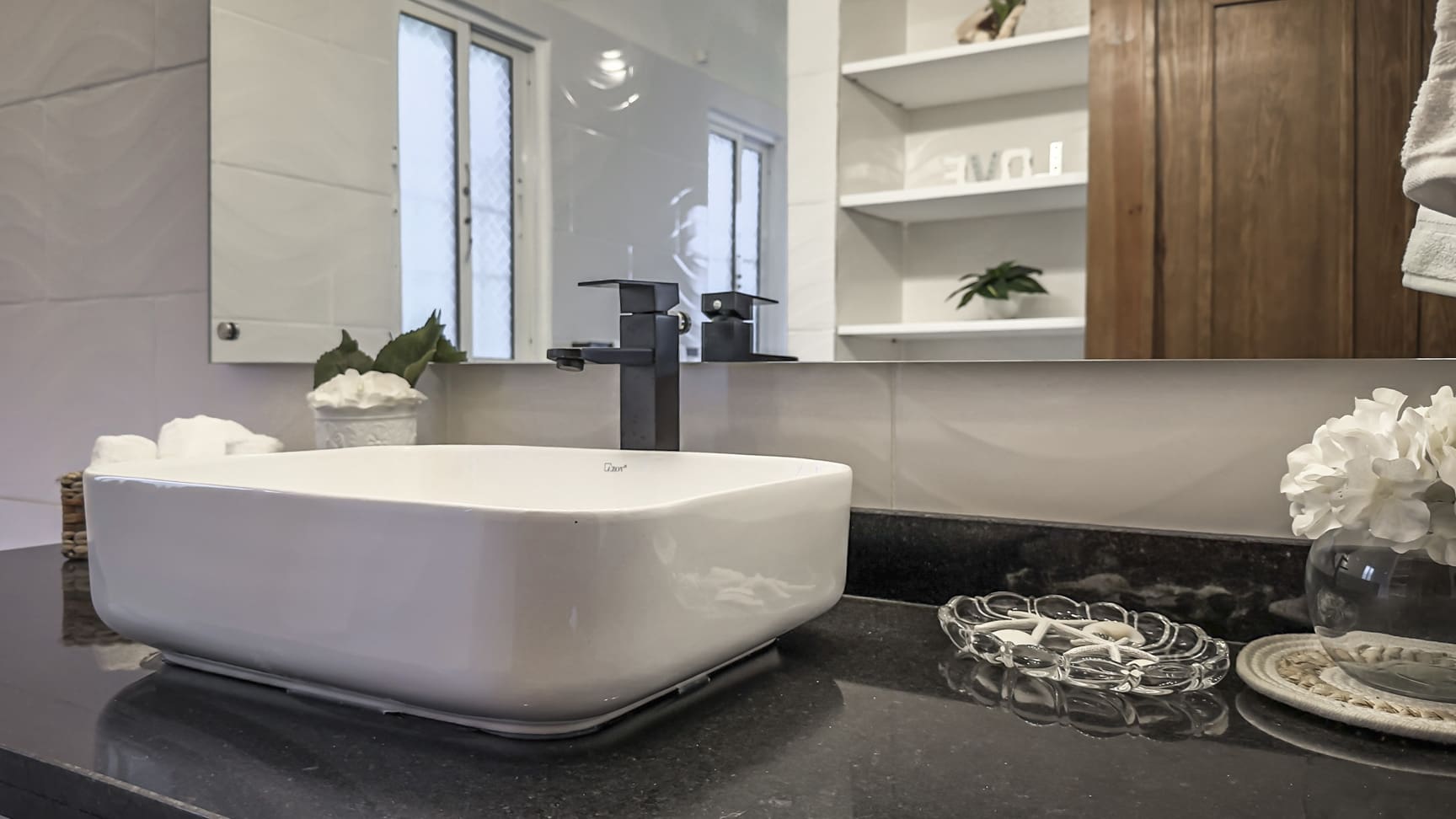 Modern bathroom with white vessel sink, black faucet, and granite countertop.