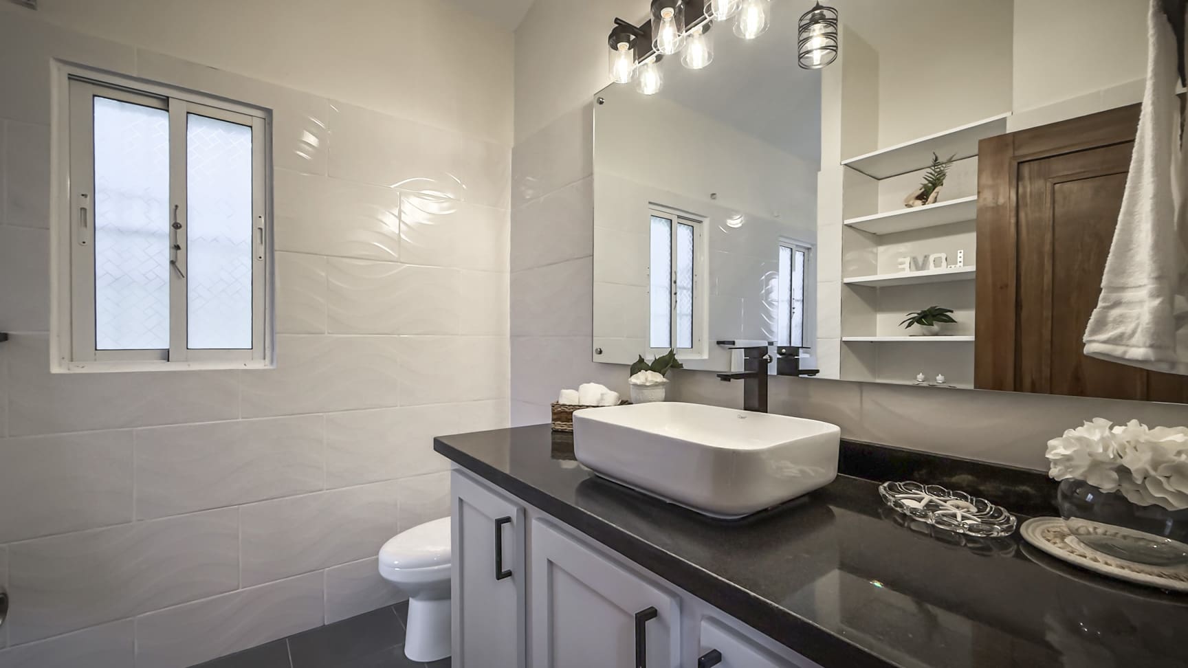 Modern white bathroom vanity with vessel sink and dark countertop