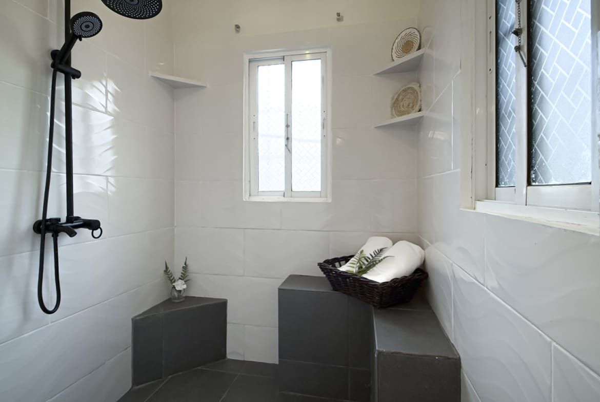 Modern white bathroom with black shower fixtures and a small window