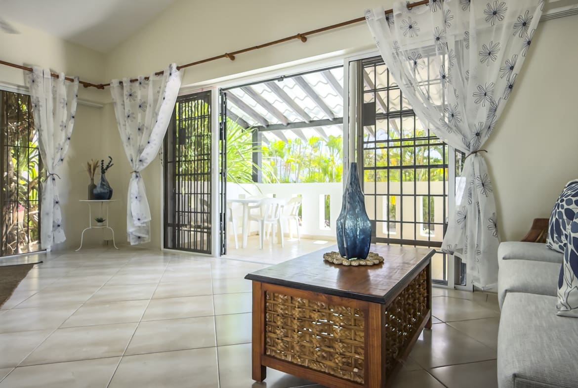 Bright living room with open patio doors leading to a covered outdoor dining area.