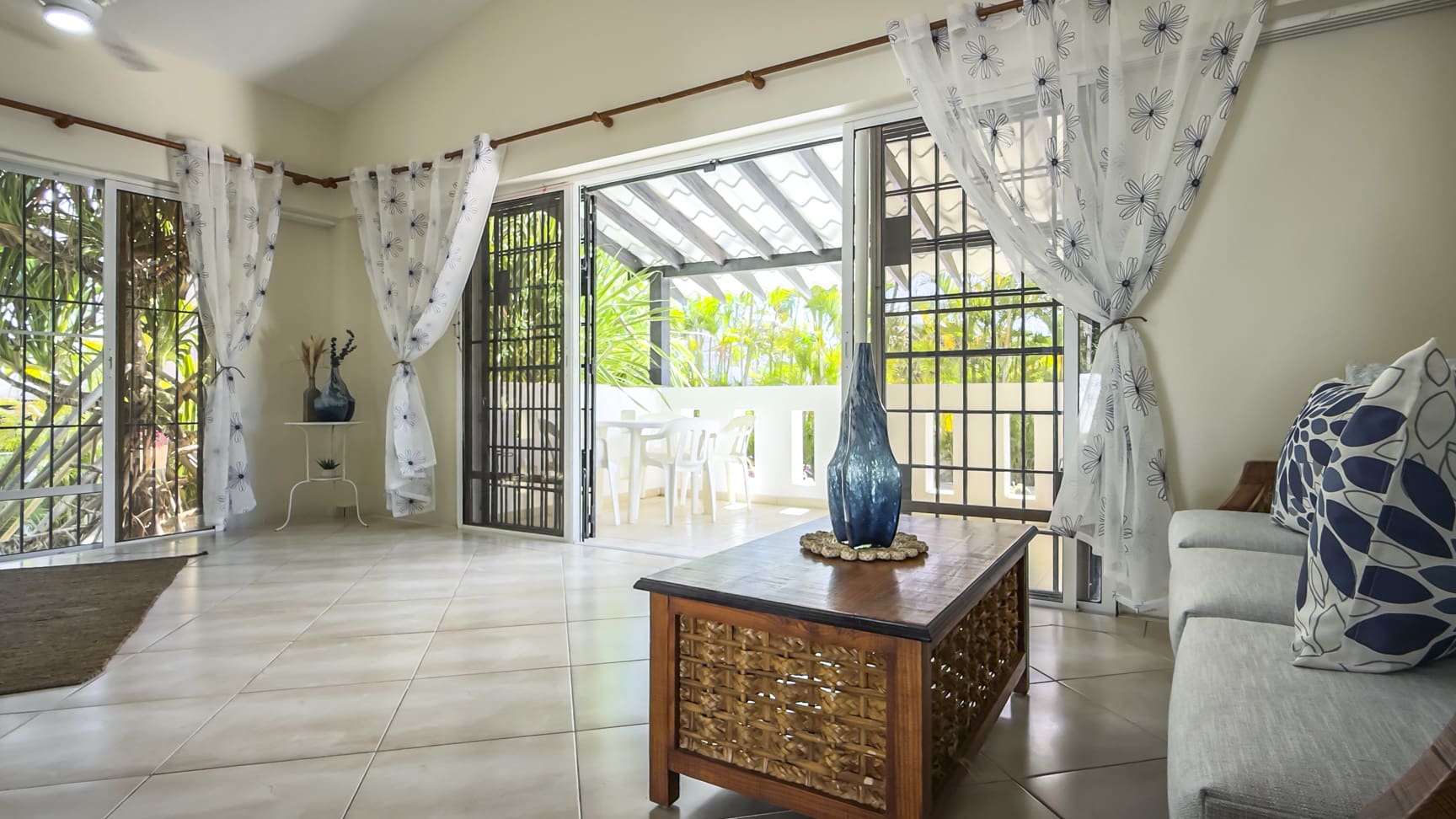 Bright living room with open patio doors leading to a covered outdoor dining area.