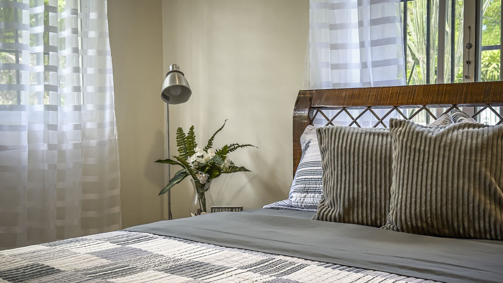 Cozy bedroom with a bed, pillows, a lamp, and sheer curtains.