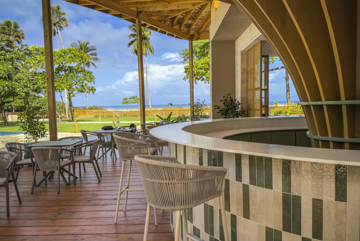 Outdoor bar with beach view, palm trees, and lounge seating