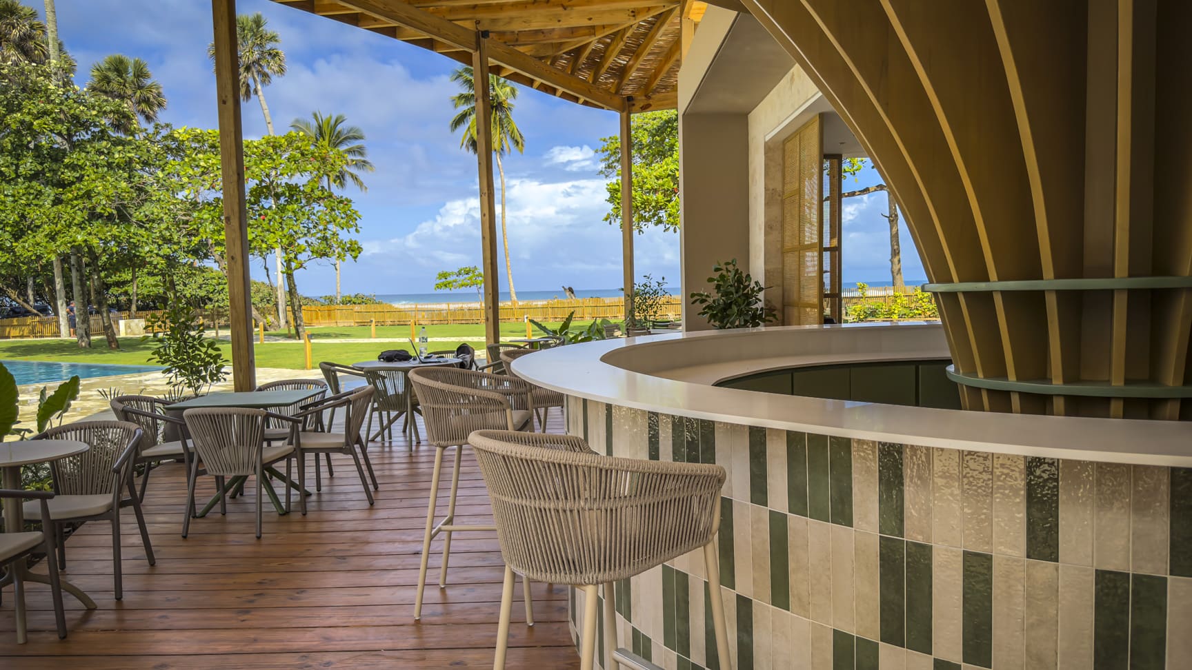 Outdoor bar with beach view, palm trees, and lounge seating