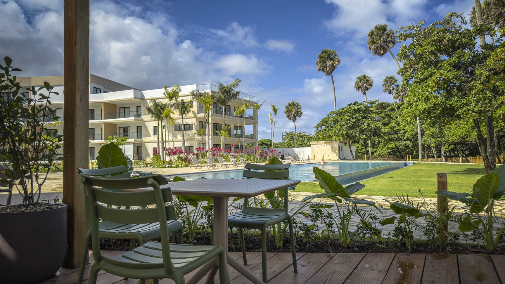 Modern resort with pool, palm trees, and tropical greenery