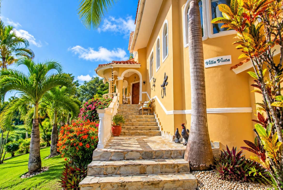 Villa Vista: Tropical luxury home entrance with palm trees and vibrant flowers.