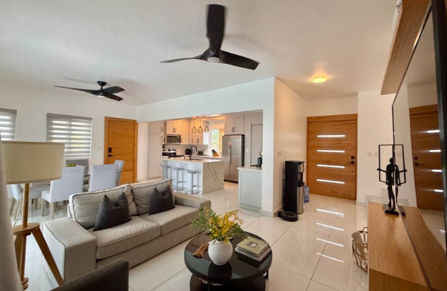 Modern living room and kitchen with island, ceiling fans, and natural light.