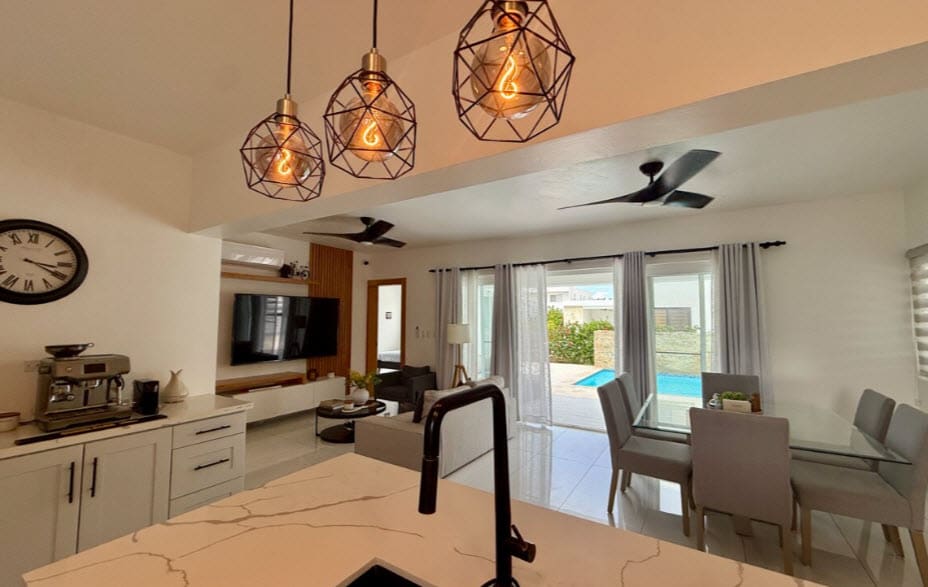 Modern kitchen and dining area with pool view, featuring pendant lights and ceiling fan.