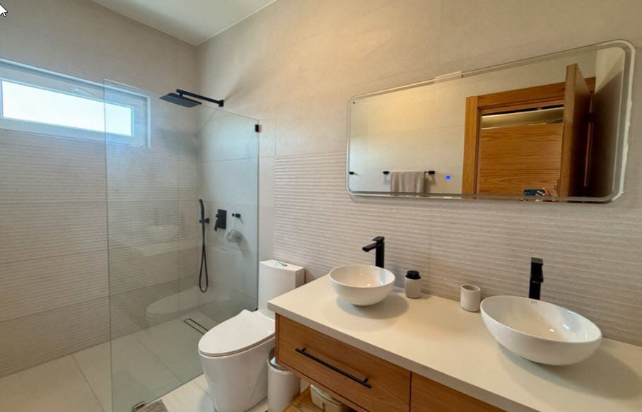 Modern bathroom with dual vessel sinks, walk-in shower, and wood vanity.