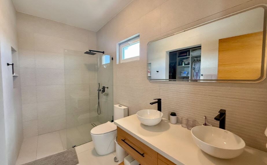 Modern bathroom with walk-in shower, floating vanity, and dual sinks.