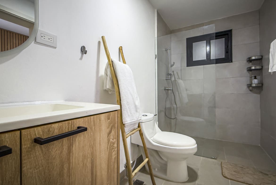 Modern bathroom with wooden vanity, white toilet, and glass shower
