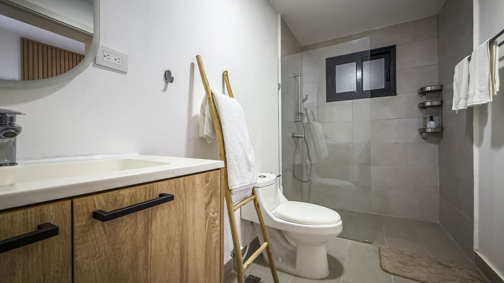 Modern bathroom with wooden vanity, white toilet, and glass shower