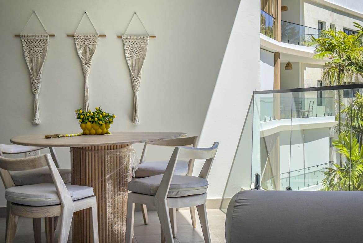 Balcony dining set with macrame wall hangings and tropical foliage