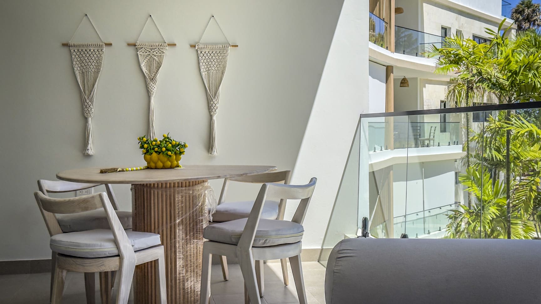 Balcony dining set with macrame wall hangings and tropical foliage