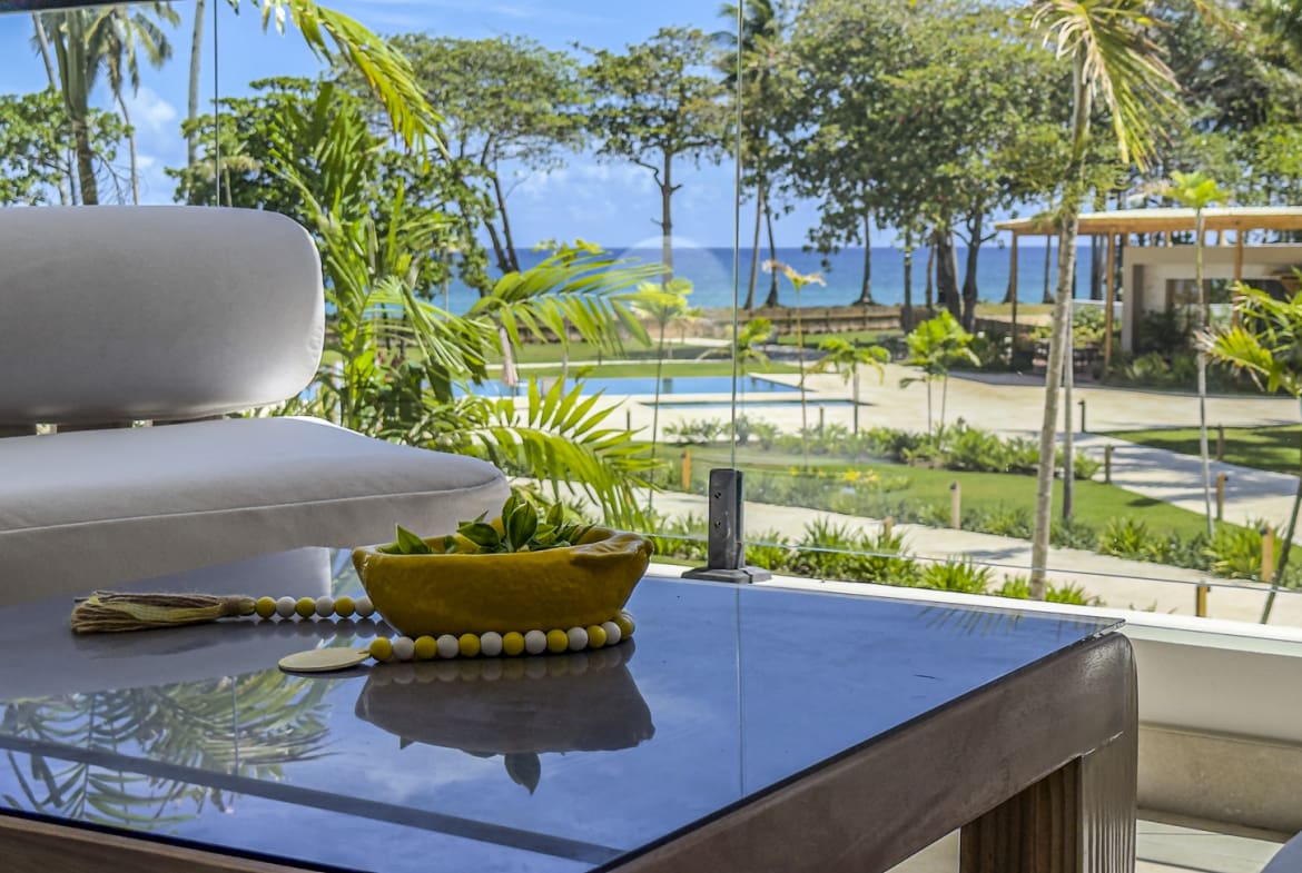 Luxury resort balcony with view of pool, ocean, and palm trees