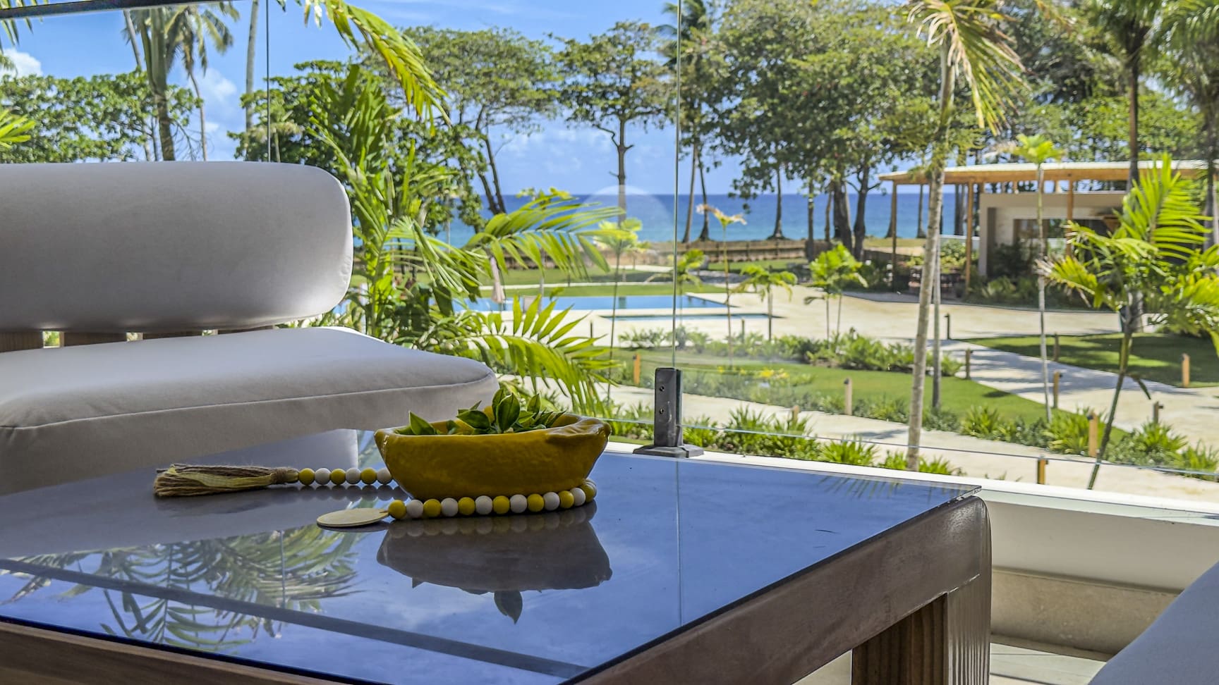 Luxury resort balcony with view of pool, ocean, and palm trees