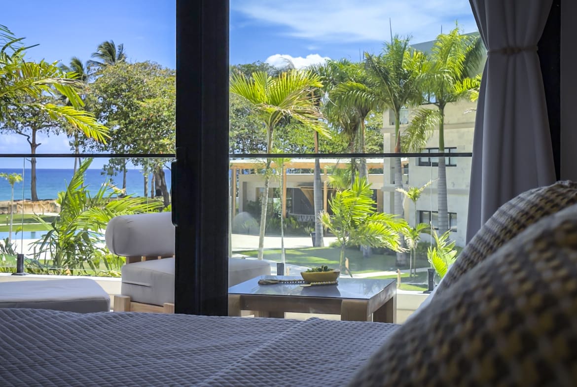 Luxury hotel room with ocean view, palm trees, and balcony.