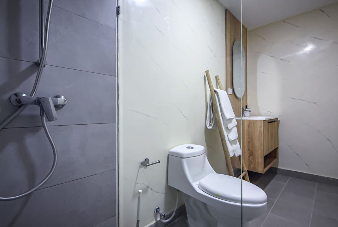 Modern bathroom with white toilet, wooden vanity, and grey shower