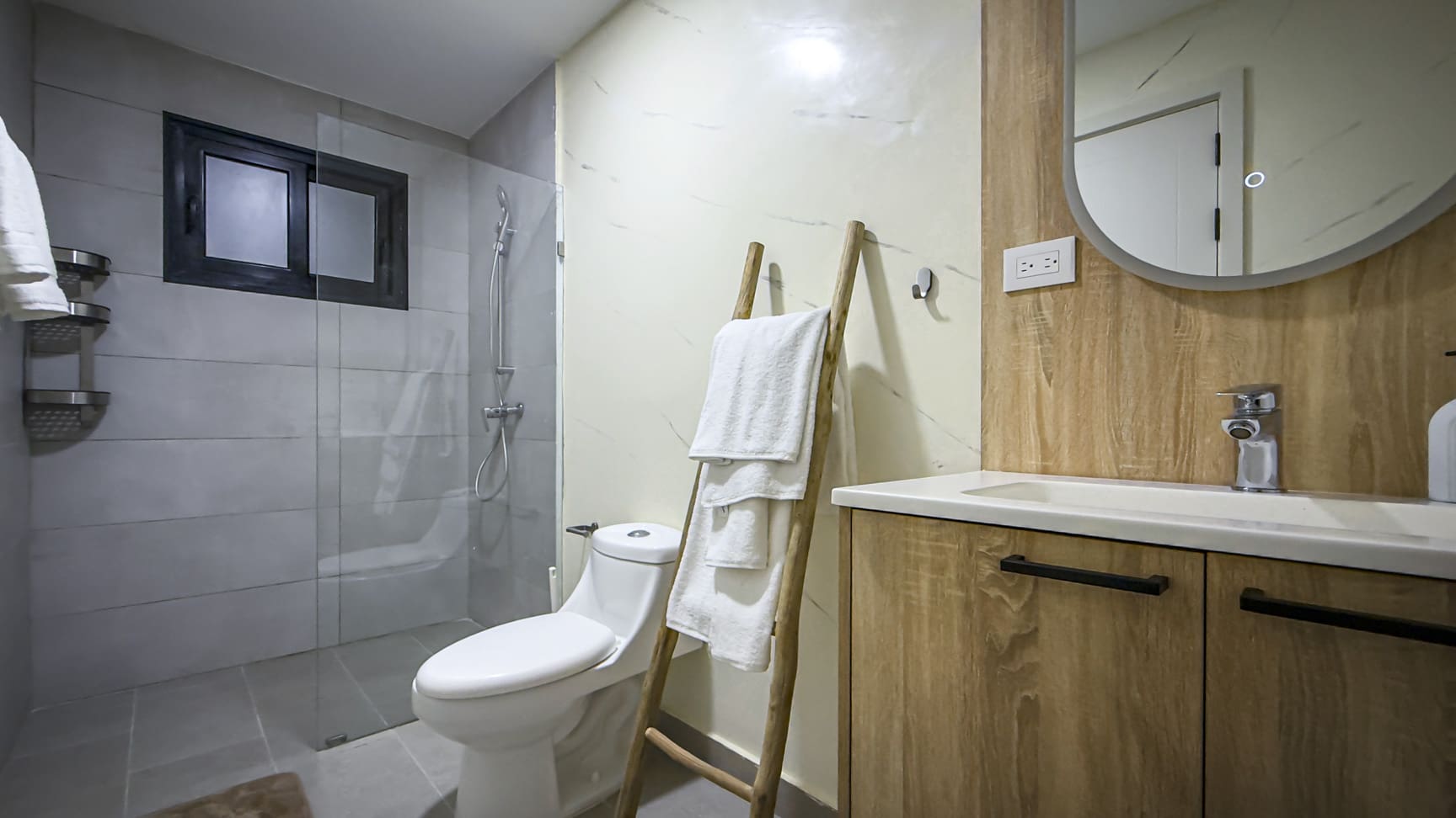 Modern bathroom with toilet, glass shower, and wood vanity with sink