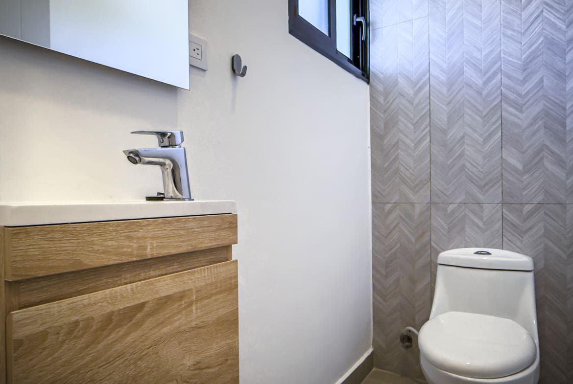 Modern bathroom with wood vanity, chrome faucet, and patterned tile wall.
