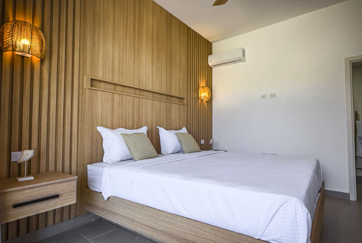 Modern bedroom with wooden accent wall, white bedding, and rattan lamps.