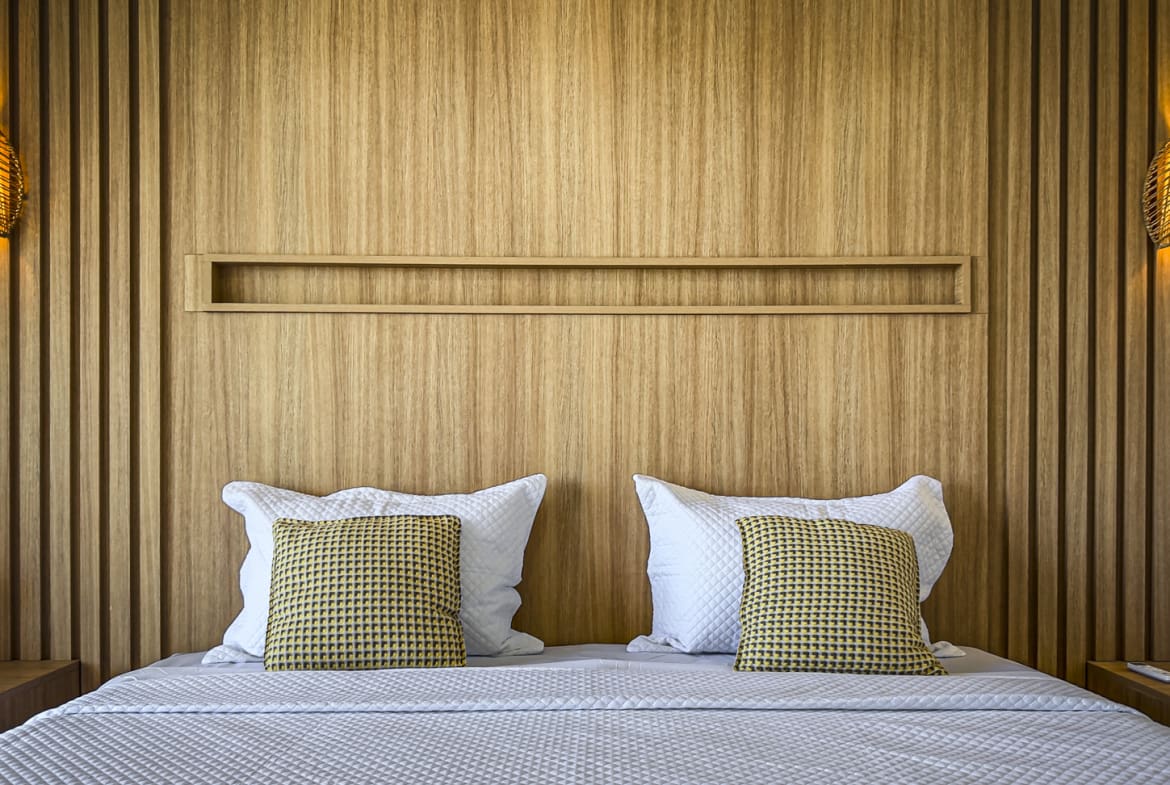 Cozy bedroom with a wooden headboard, textured pillows, and woven lamps.