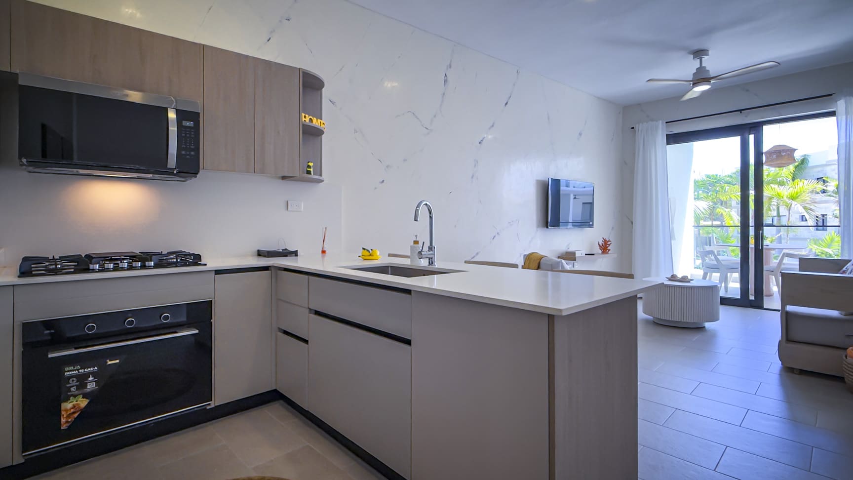 Modern kitchen and living area with sleek cabinetry, stainless steel appliances, and natural light