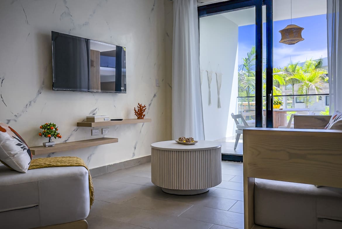 Modern living room with marble accent wall, TV, and balcony view.