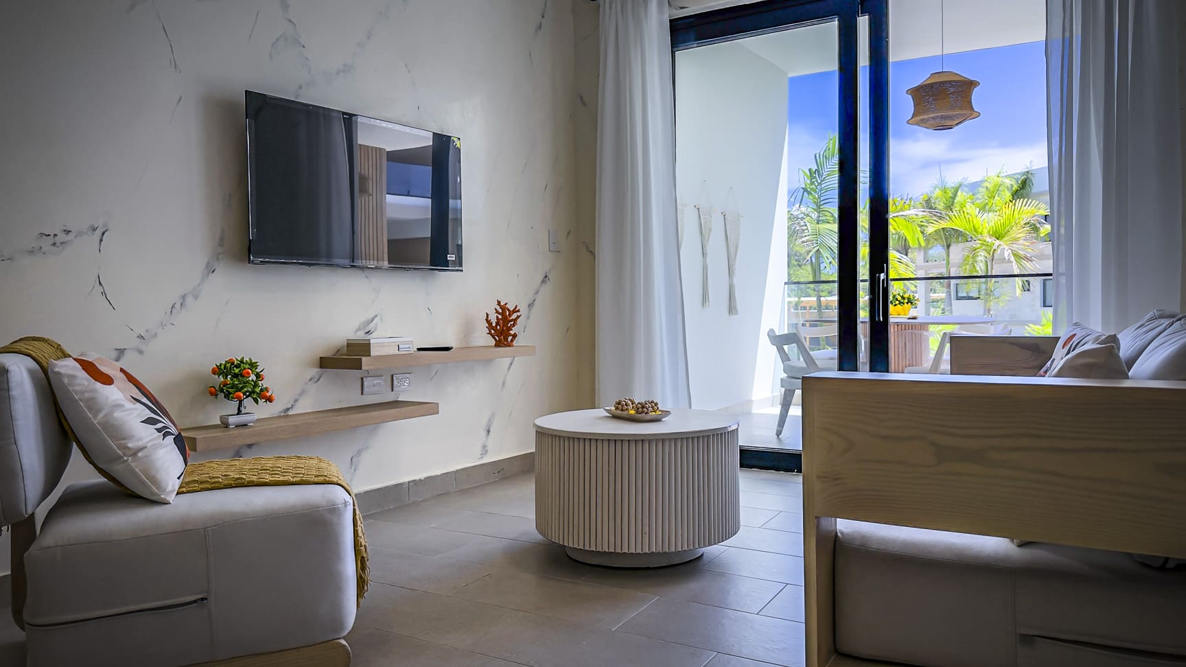 Modern living room with marble accent wall, TV, and balcony view.