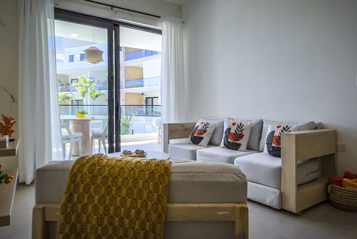 Bright living room with white sofa, yellow throw, and balcony view